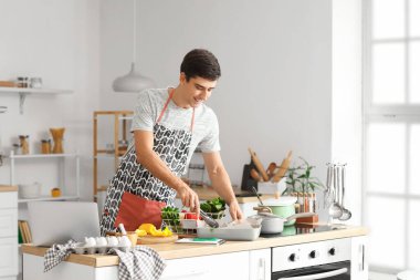 Genç adam mutfakta yemek yapıyor.