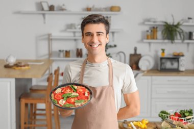 Mutfakta lezzetli pizzası olan genç adam.