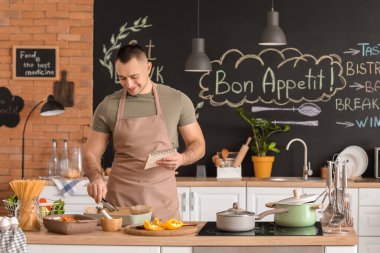 Genç adam mutfakta yemek yapıyor.