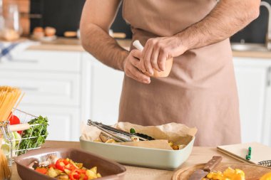 Genç adam mutfakta yemek yapıyor.