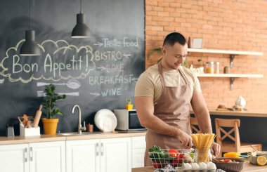 Genç adam mutfakta yemek yapıyor.