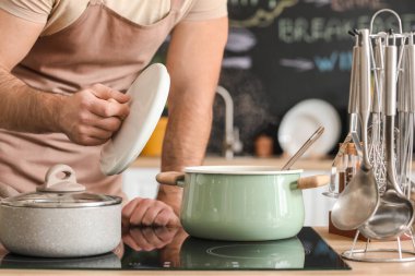 Genç adam mutfakta yemek yapıyor.