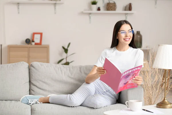 Young Woman Wearing Glasses While Reading Magazine Home — Stock Photo, Image