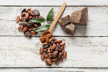 Kakao çekirdekli kaşık ve tereyağı beyaz ahşap arka planda