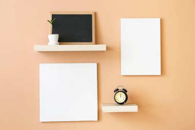 Çalar saati olan raflar ve duvarda asılı boş posterler.