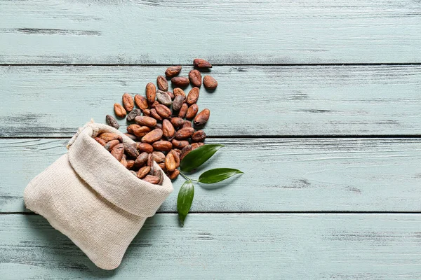 Beutel Mit Kakaobohnen Auf Farbigem Holzhintergrund — Stockfoto