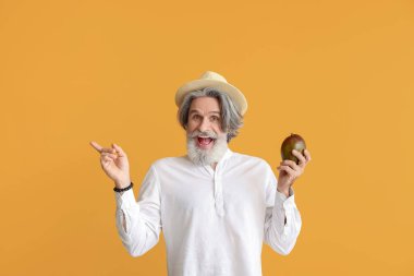 Mangolu yaşlı adam renk arkaplanına işaret ediyor.