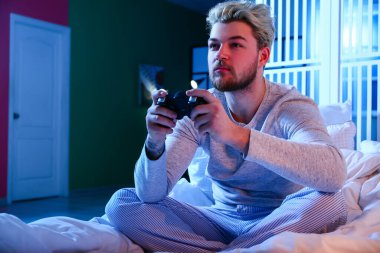 Genç adam gece geç saatlerde evde video oyunu oynuyor. Bağımlılık kavramı