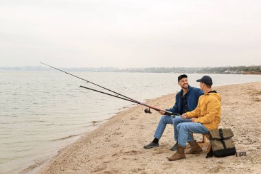 Baba ve oğul nehirde birlikte balık tutuyorlar.