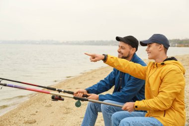 Baba ve oğul nehirde birlikte balık tutuyorlar.