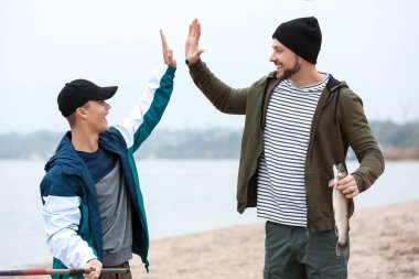 Nehir kıyısında balık yakalayan mutlu baba ve oğul