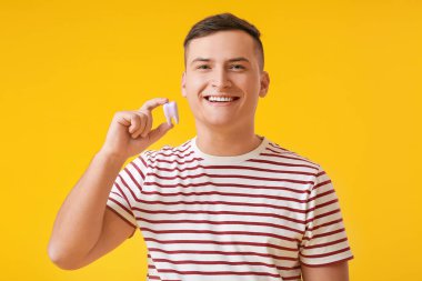 Renkli arka planda plastik dişli genç adam.