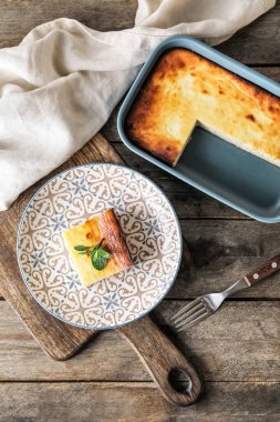 Ahşap arka planda süzme peynirli güveç tabağı.