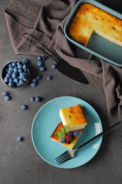 Koyu arkaplanda süzme peynir güveci olan bir tabak.