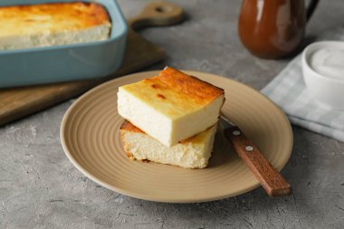 Grunge arka planında süzme peynir güveci parçaları olan tabak.