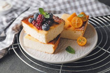 Koyu arkaplanda süzme peynir güveci olan bir tabak.