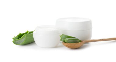 Beyaz arka planda aloe parçaları olan doğal krema ve kaşık kavanozları.