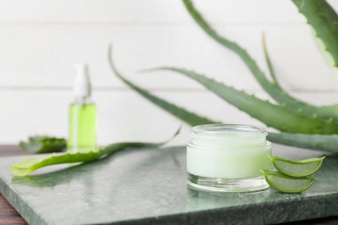 Doğal kremalı kavanoz ve mermer zemin üzerinde aloe parçaları