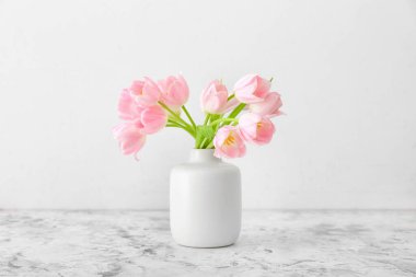 Açık arkaplanda güzel lale çiçekleri olan vazo.