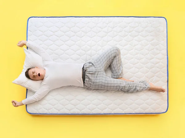 Young Man Lying Soft Mattress Color Background — Stock Photo, Image