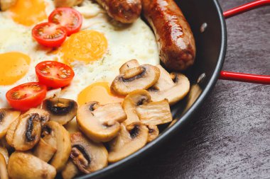 Koyu arka planda lezzetli kahvaltılı tava, yakın plan.