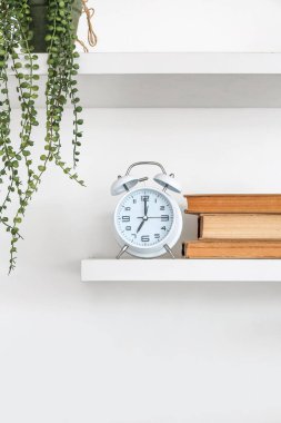 Işık duvarında çalar saat asılı kitap rafları