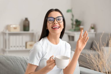 Genç bayan evde kahve içiyor.