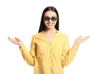 Beyaz arka planda şık güneş gözlüğü takan güzel genç bir kadın.