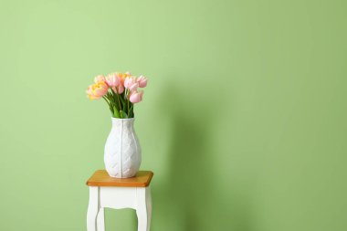 Renkli duvarın yanındaki masada bir buket lale çiçeği.