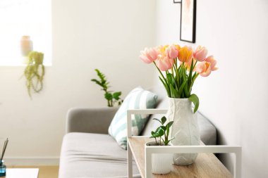 Oturma odasının içindeki rafta güzel lale çiçekleri var.