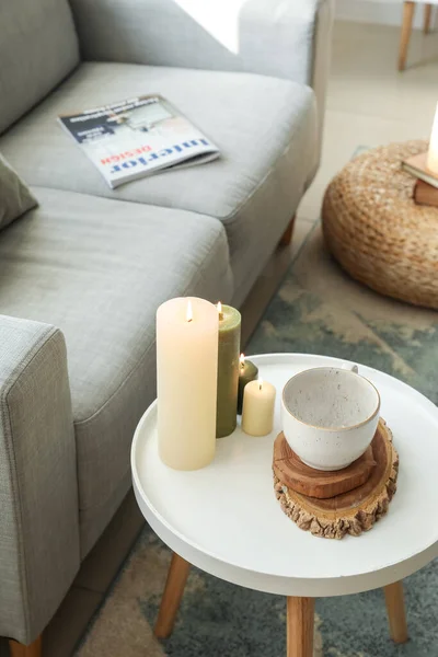 Burning candles on table in stylish living room
