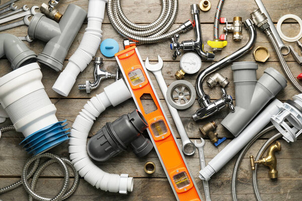 Set of plumber's items on wooden background