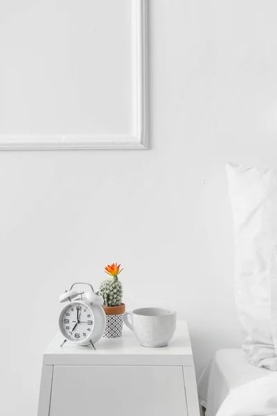 Wecker Und Tasse Auf Tisch Neben Lichtwand Schlafzimmer — Stockfoto