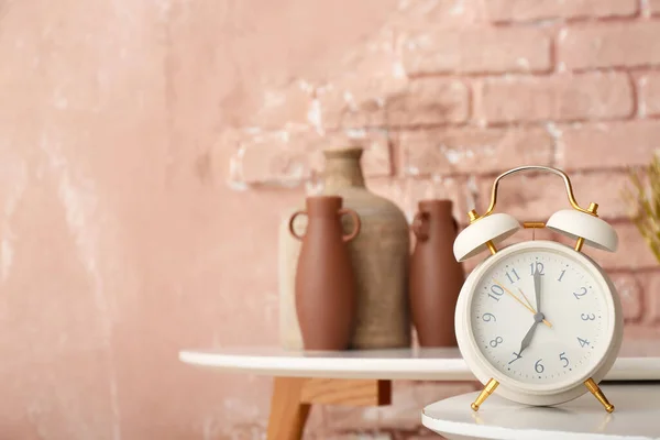 カラーレンガの壁の近くのテーブルの上の目覚まし時計 — ストック写真