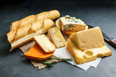 Farklı peynir türleri ve koyu arkaplanda taze ekmek.