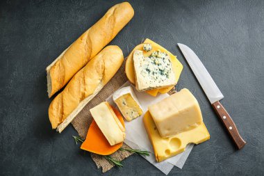 Farklı peynir türleri ve koyu arkaplanda taze ekmek.