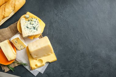 Farklı peynir türleri ve koyu arkaplanda taze ekmek.