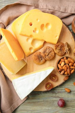 Ahşap arka planda lezzetli peynirli, fındıklı ve kurutulmuş incirli tahta, yakın plan.