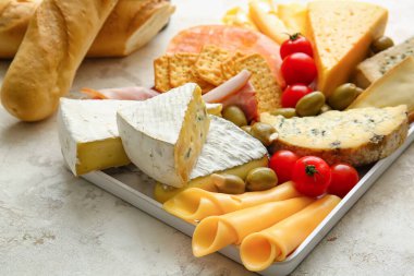 Farklı peynir türleri ve hafif arka planda atıştırmalıklar içeren tepsi, yakın plan