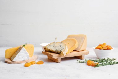 Açık arkaplanda farklı peynir ve kurutulmuş kayısılar var.