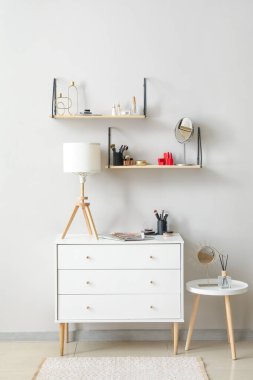Dekoratif kozmetik ürünleri olan raflar ve odanın ışık duvarı yakınındaki çekmeceler.