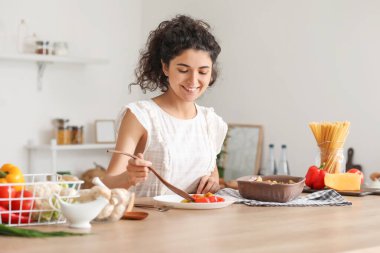 Genç bir kadın mutfağa lezzetli yemekler koyuyor.