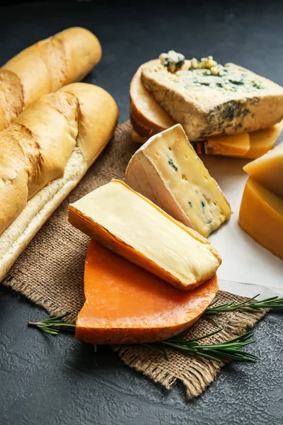 Farklı peynir türleri ve koyu arkaplanda taze ekmek.