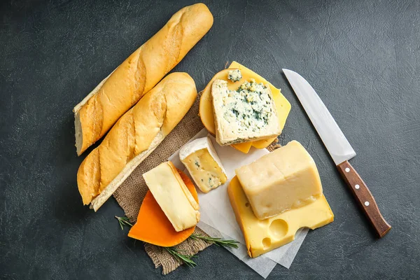 Farklı peynir türleri ve koyu arkaplanda taze ekmek.
