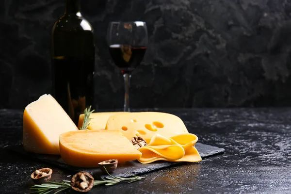 Tasty cheese, walnuts and wine on dark background, closeup