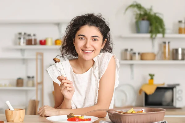 年轻女人在厨房里吃着美味的菜 — 图库照片