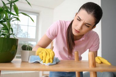 Odadaki masaları temizleyen genç bayan.