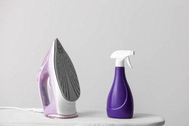 Işık arkaplanındaki elektrikli ütü ve tahta