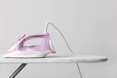 Işık arkaplanındaki elektrikli ütü ve tahta