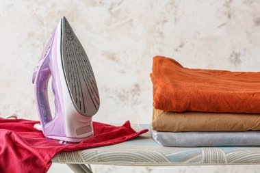 Açık arkaplanda elektrikli ütü ve temiz giysiler